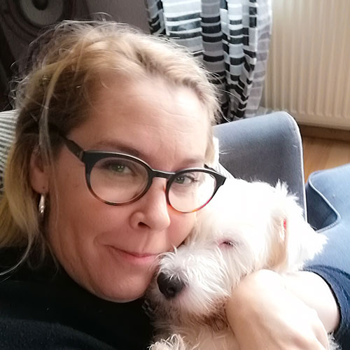 Marika Parkkomäki kramar en liten vit hund